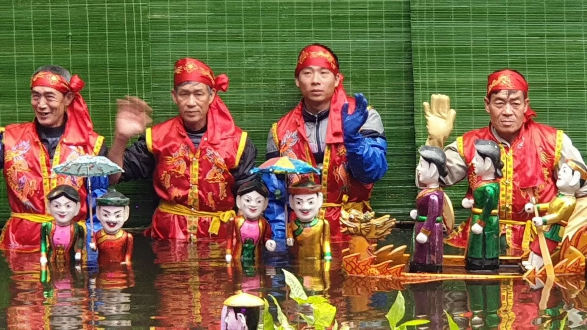 Water puppeteers controlling the puppets behind a bamboo screen