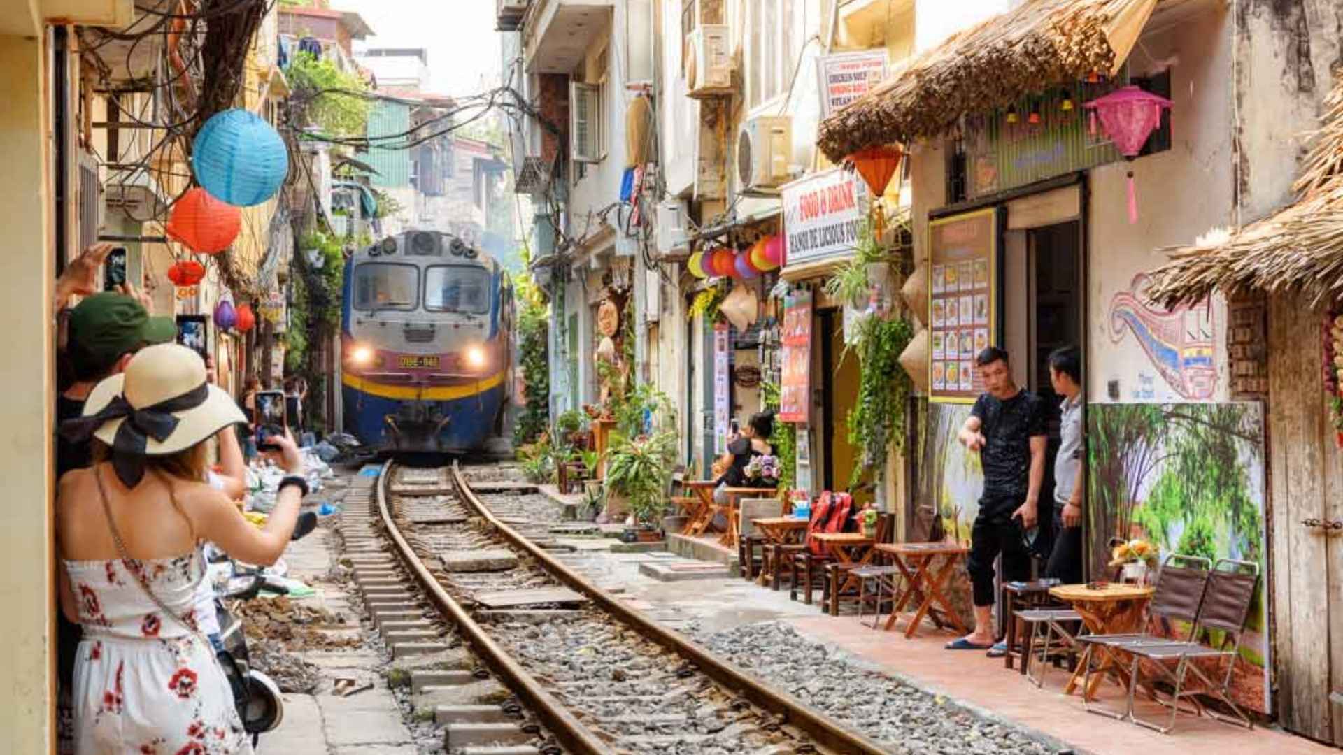 A narrow alley lined with cafés and houses, where a train passes just inches away.