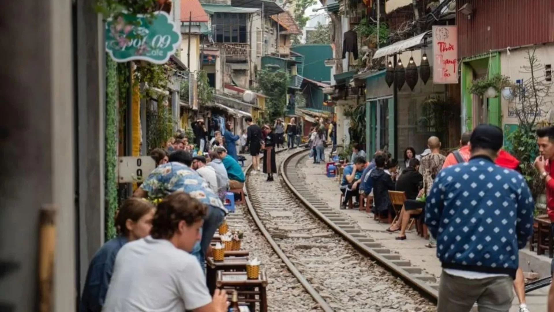 A vibrant alley with cozy cafés and shops along the railway tracks.