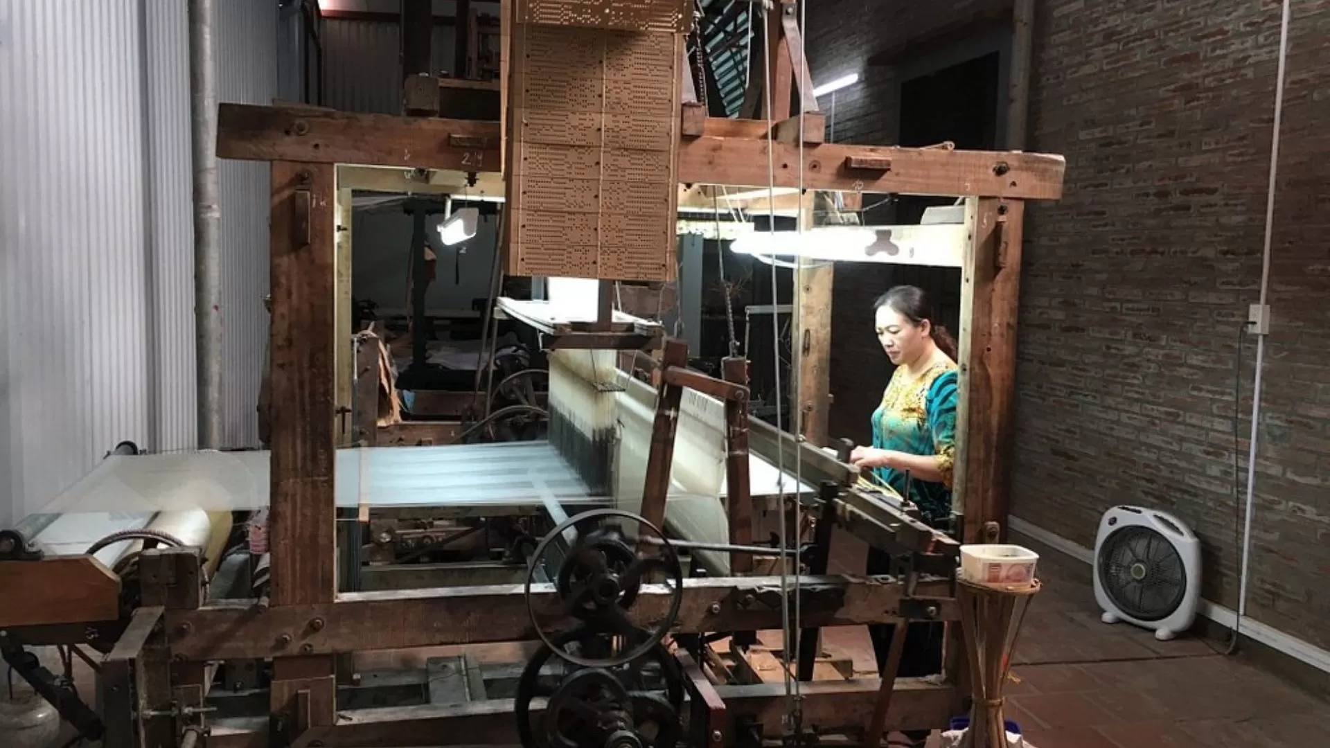Artisan operating a loom to weave silk at Van Phuc village.